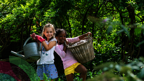 Twee meisjes in de tuin met tuingereedschap