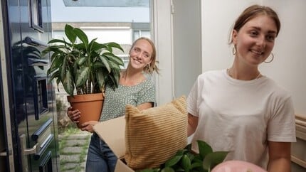 twee jonge vrouwen met spullen in gang van woning
