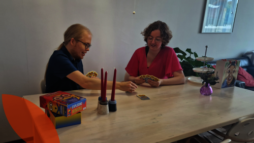 Freeke en Loes spelen een kaartspel aan tafel